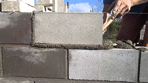 Цементный раствор наносят при помощи шпателя, равномерно распределяя его по блоку